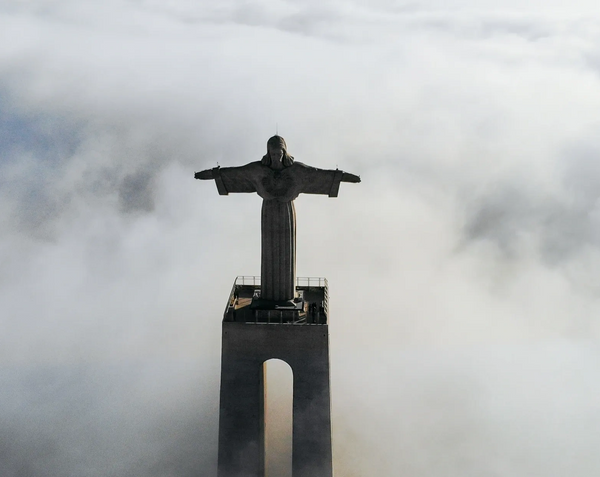 Statue of Jesus Christ with open arms appearing above the clouds. 
