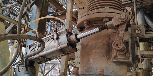 Industrial tie-rod hydraulic cylinder installed on heavy process equipment.