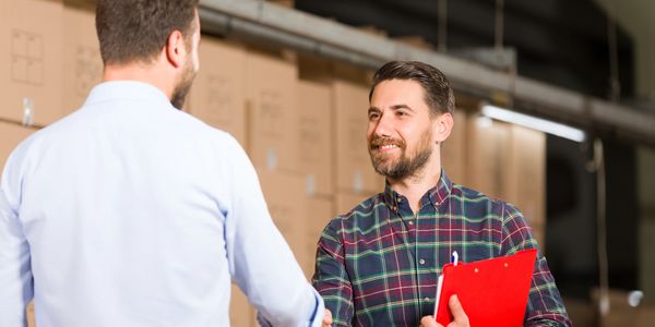 Two men shaking hands, one holding a clipboard.