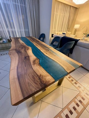 Wood and blue resin river dining table with gold legs in a modern living room.