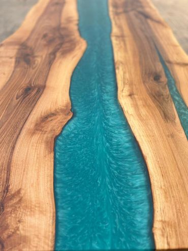 Wooden table with blue resin river design flowing through the center.