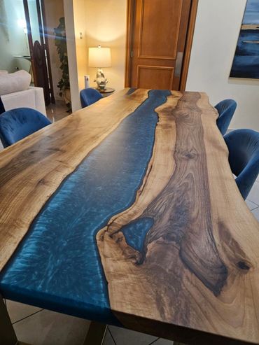 Elegant wooden table with blue resin river and blue velvet chairs.
