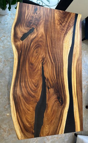 Polished wooden table with natural grain and black resin accents.