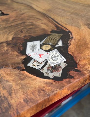 Playing cards and a coin resting in a natural wooden table hollow.
