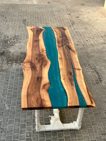 Wood and blue resin river table on a tiled floor.