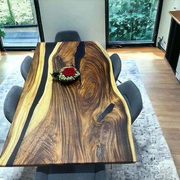 Elegant wooden dining table with a centerpiece of red roses and greenery.