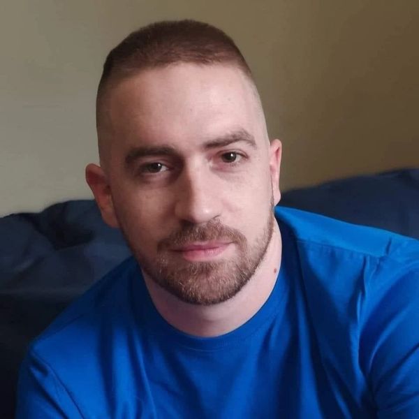 Man with a short haircut and beard wearing a blue shirt.