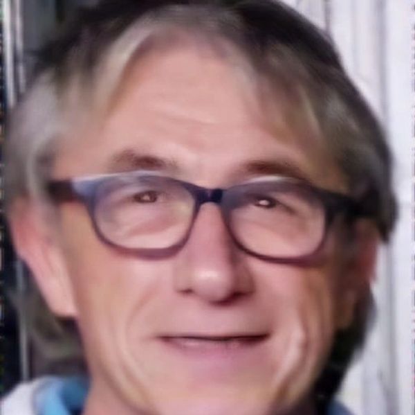 Smiling man wearing glasses with gray hair.