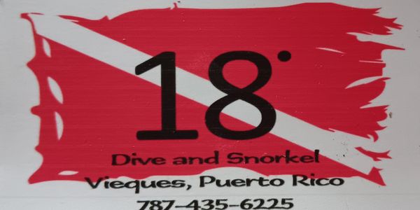 A red and white diver down flag with '18° Dive and Snorkel Vieques, Puerto Rico' text and phone number.
