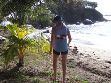 Woman standing on a tropical beach near palm trees.