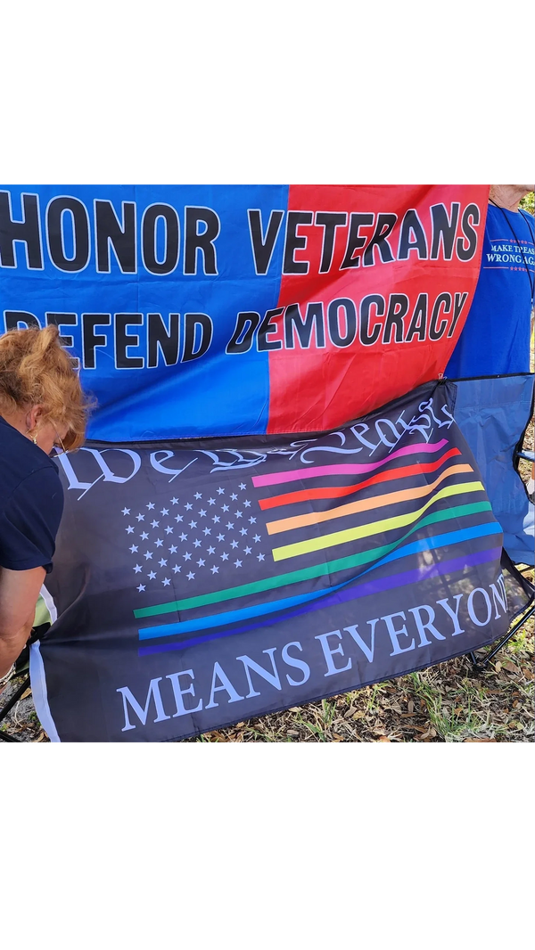 People putting up  “honor veterans, defend democracy” and “We the People Means Everyone” banners.