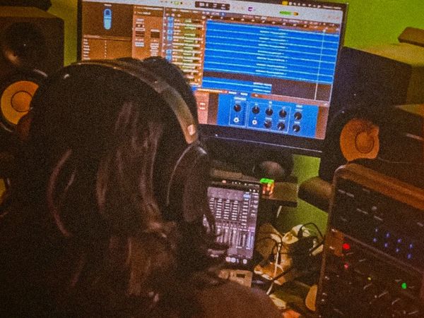 Person with headphones in a music studio working on a digital audio workstation.