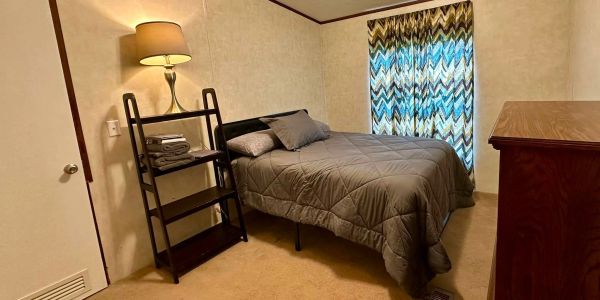 Cozy bedroom with a bed, lamp, and patterned curtains.