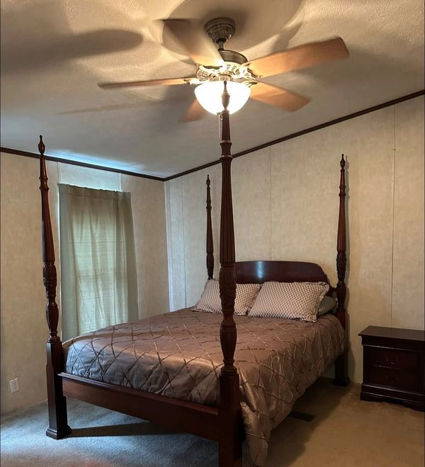 Cozy bedroom with a four-poster bed and ceiling fan.