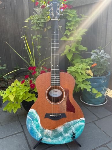 Acoustic guitar with ocean wave art on its body.