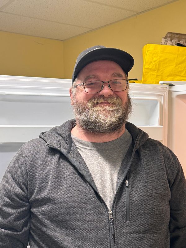 Smiling man with glasses and beard in casual wear indoors.