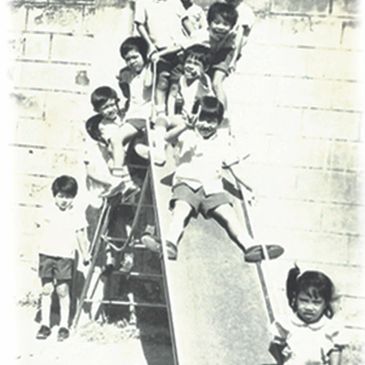 A group of children playing on a slide in a black and white photo.