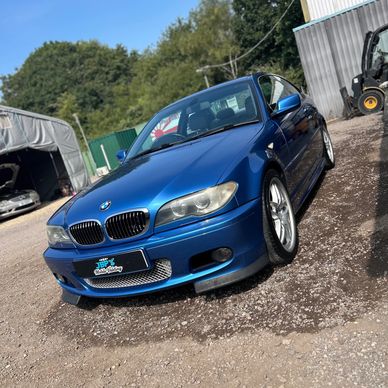 Blue BMW car parked outdoors on a gravel surface.