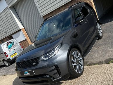 Gray Range Rover parked on a driveway near a building.