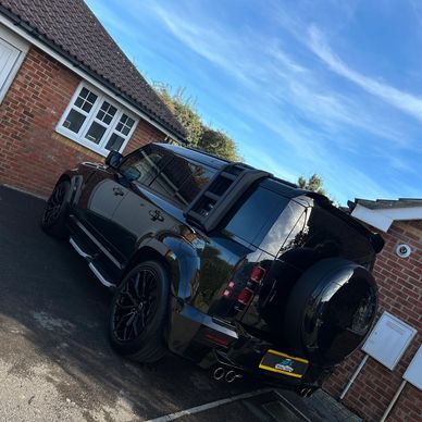 Black SUV parked next to a brick house.