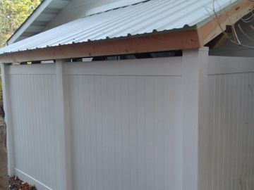 White vinyl fence with a metal roof attached to a house.