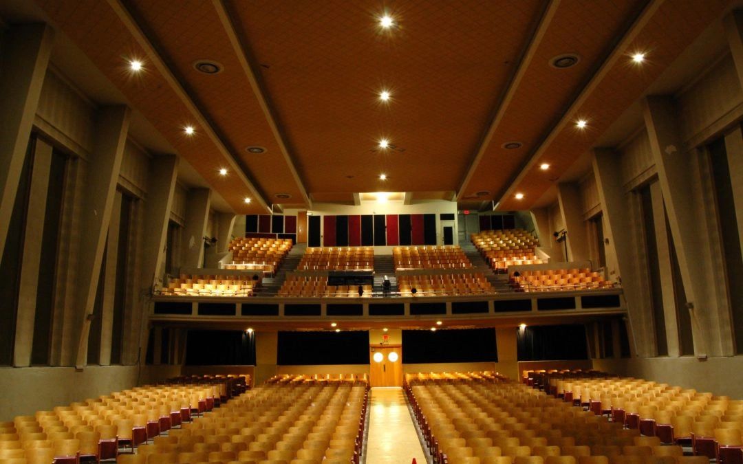 Une salle de théâtre vide avec des sièges en bois.