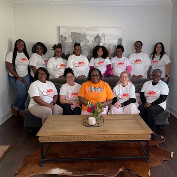 Group photo of twelve women in matching shirts indoors.