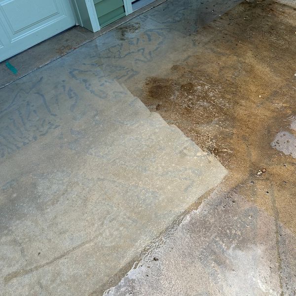 Partially cleaned concrete driveway with visible dirt and grime.