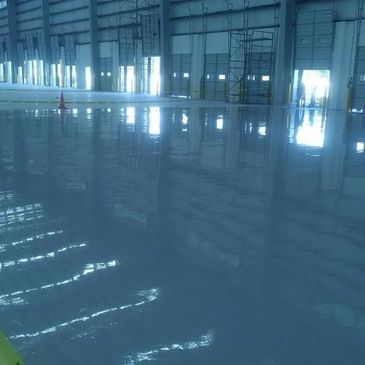 Shiny, freshly polished concrete floor inside a large industrial warehouse.