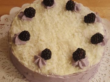 White cake with layers of blackberry filling. Vanilla frosting. Fresh blackberries and sweet coconut