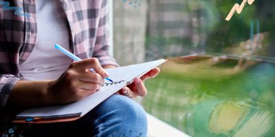Woman sitting at window writing in journal