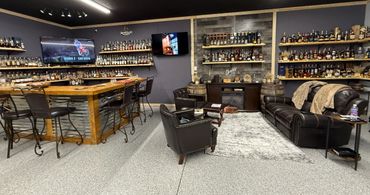 A cozy home bar with leather seating and extensive liquor shelves.