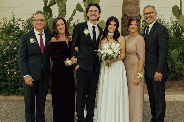 A happy wedding couple with their proud family posing outdoors.