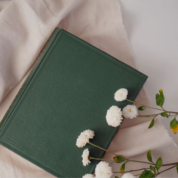 Green journal with white flowers, symbolizing new beginnings and growth.