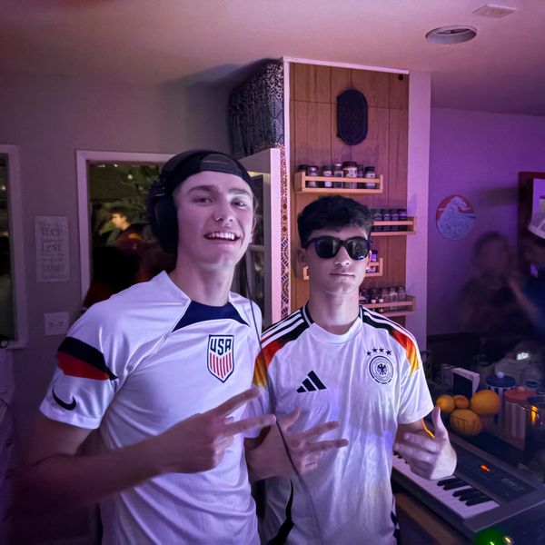 Two young men wearing sports jerseys indoors.