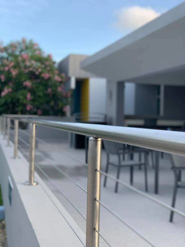 Modern outdoor patio with stainless steel railing and seating area.