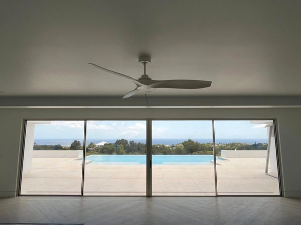 Modern room with large glass doors overlooking a pool and scenic ocean view.