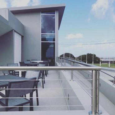 Modern outdoor terrace with metal railing and seating under a clear sky.
