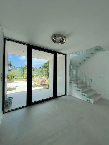 Modern minimalistic interior with glass staircase and large window.