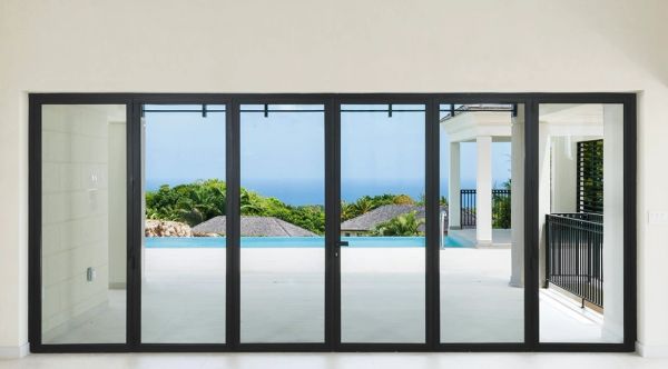 Modern glass doors open to a pool with ocean views.
