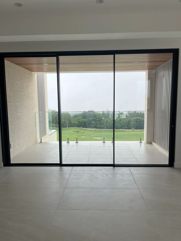 Modern balcony with glass railing overlooking a green golf course.