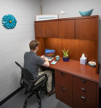 Member working in private office at desk, on laptop.