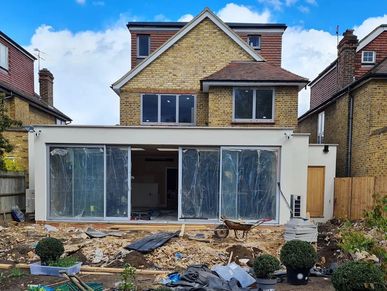 A house undergoing renovation with an extended ground floor and construction materials outside.