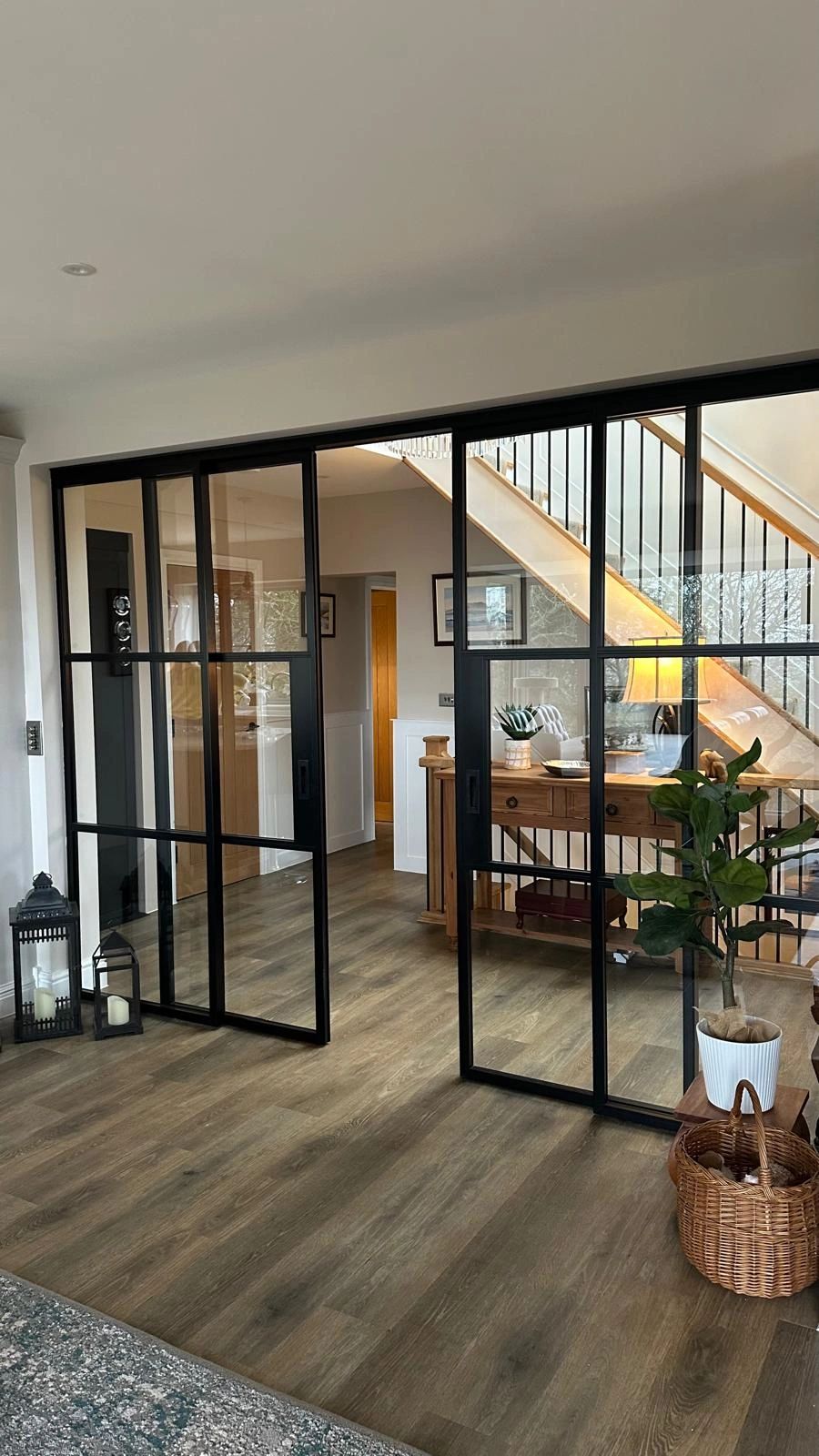 Modern interior with black-framed glass sliding doors and wooden flooring.