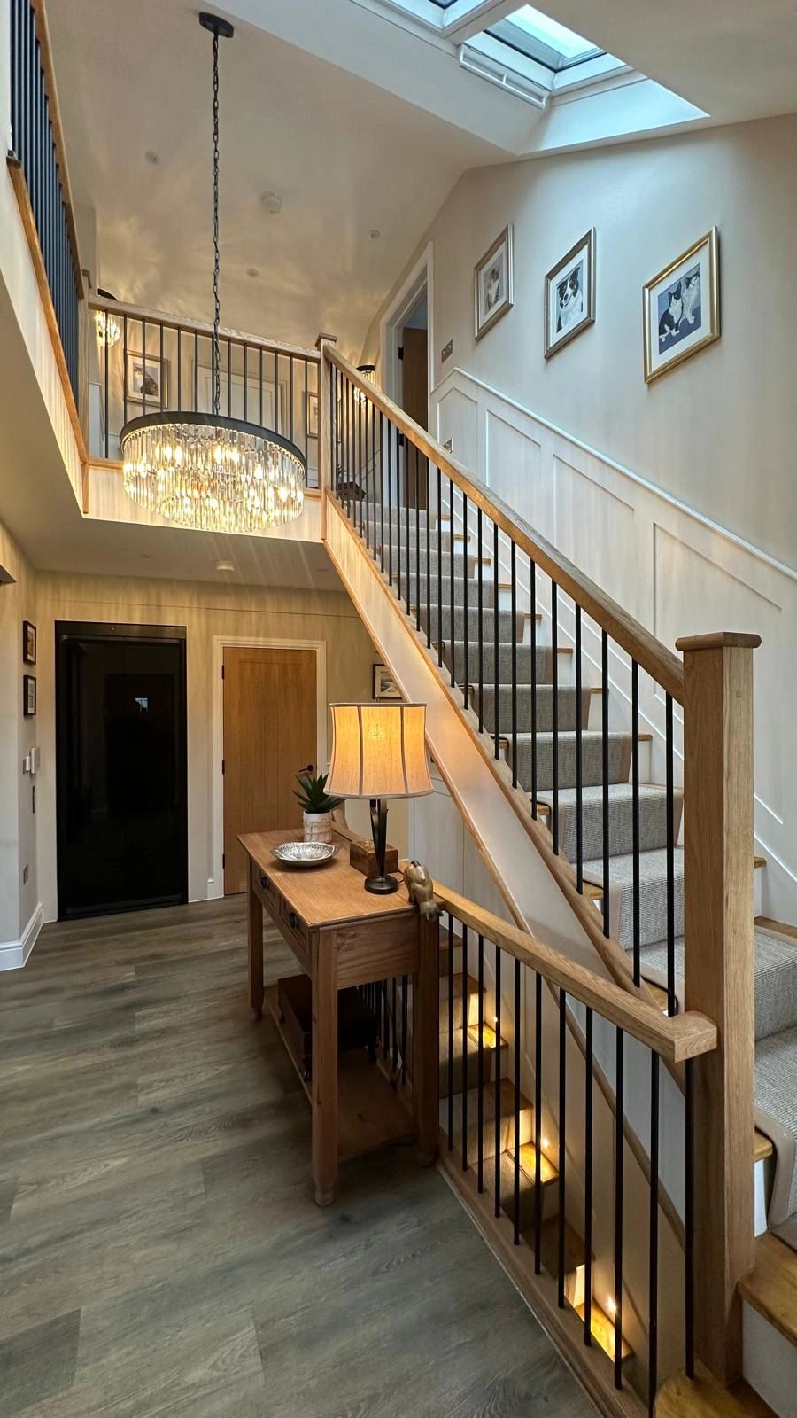 Elegant staircase with wood and metal railing, soft lighting, and decorative artwork.