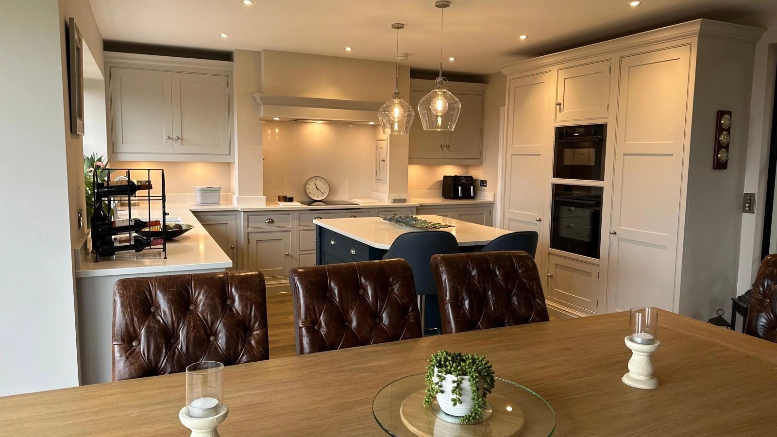 Modern kitchen with leather chairs, island, and warm lighting.