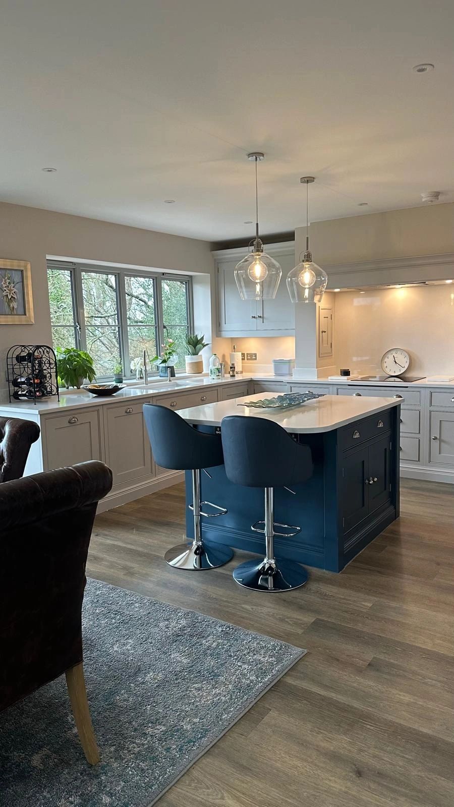 Modern kitchen with blue island and pendant lights.
