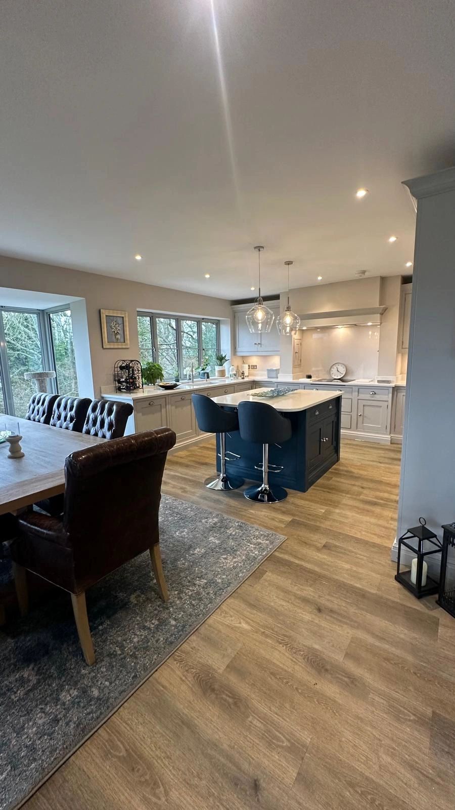 Modern kitchen with blue island and leather dining chairs.