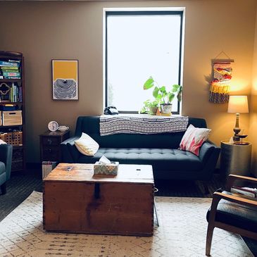 Cozy living room with a vintage wooden chest and a blue sofa under a bright window.