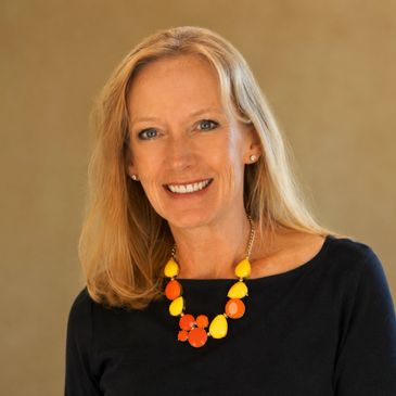 Smiling woman with blonde hair wearing a colorful necklace and black top.